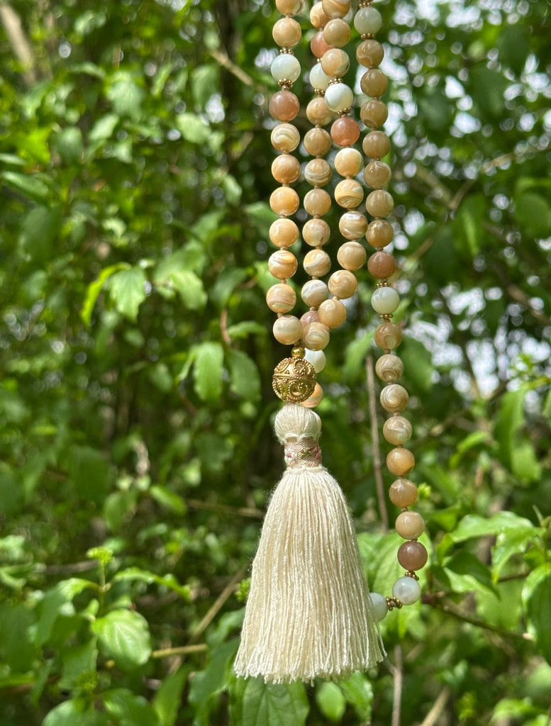 Mala 108 grani madreperla e pietra luna cipria appesa ad un albero per effetto naturale.