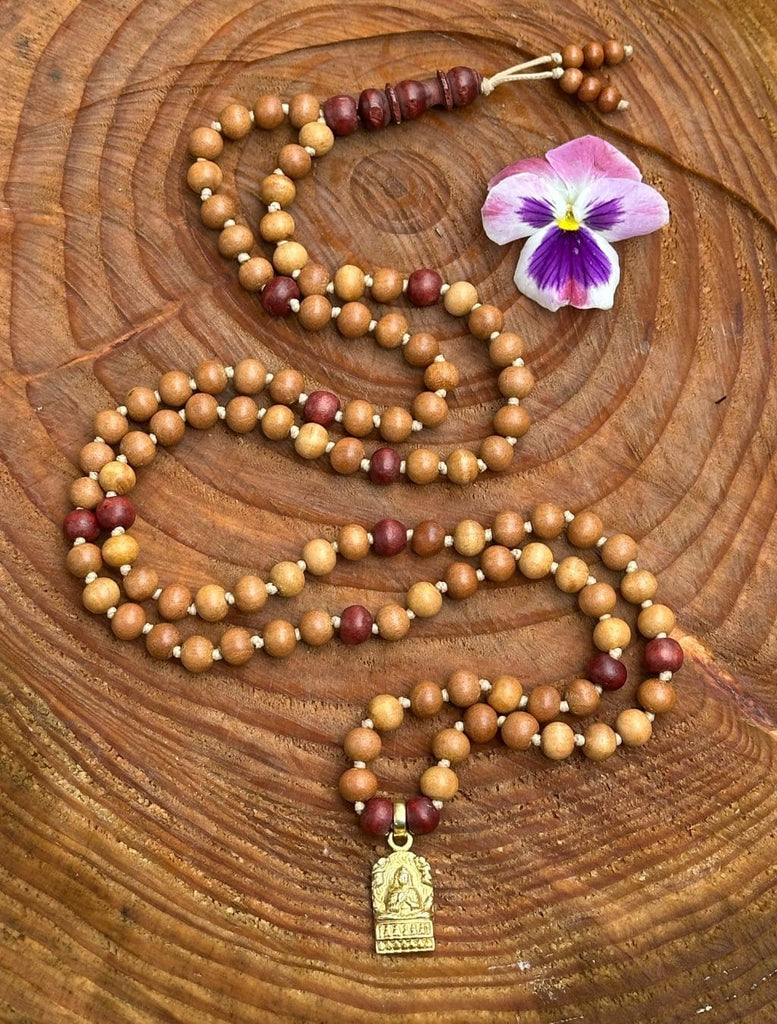 Mālā Vesak distesa su superficie di legno, 108 grani e pendente Buddha dorato.