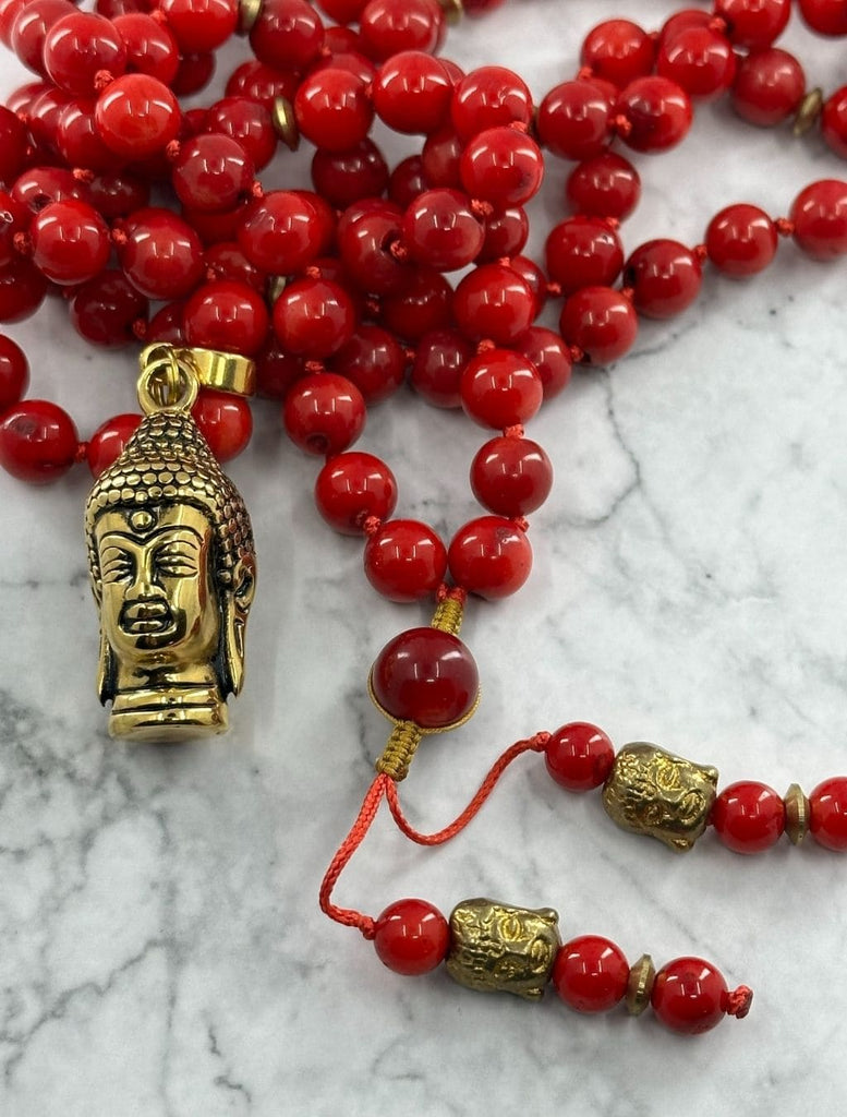 Mala 108 grani di corallo bambù: zoom sui piccoli Buddha in ottone posti sui laccetti terminali.