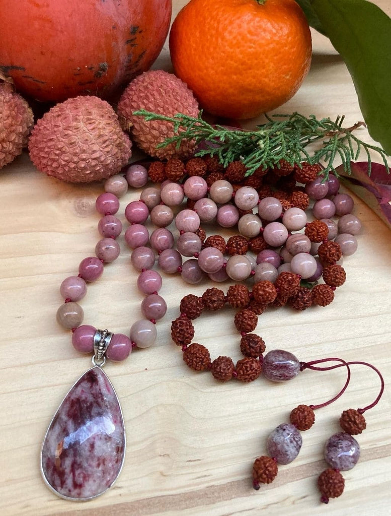 japamala fatto a mano con pietre di rodonite e semi sacri di rudraksha. Zoom su tutti i dettagli della lavorazione artigianale e sul pendente argento in quarzo fragola