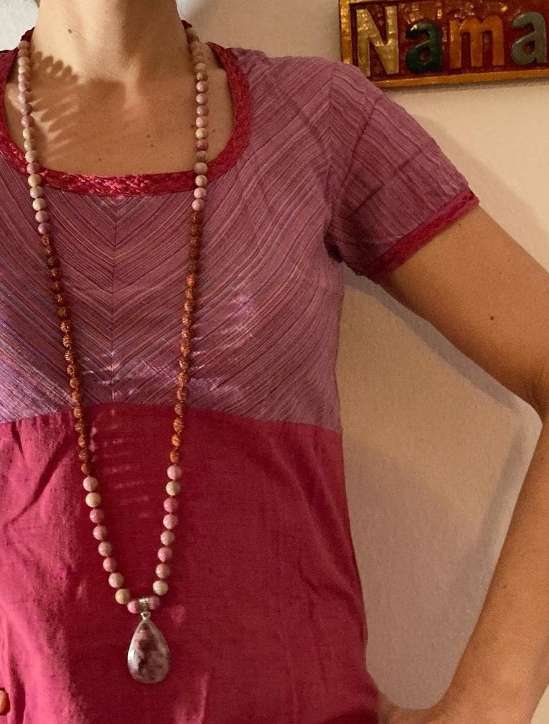 japamala fatto a mano con pietre di rodonite e semi sacri di rudraksha. Indossato nella sua lunghezza per mostrare il suo design