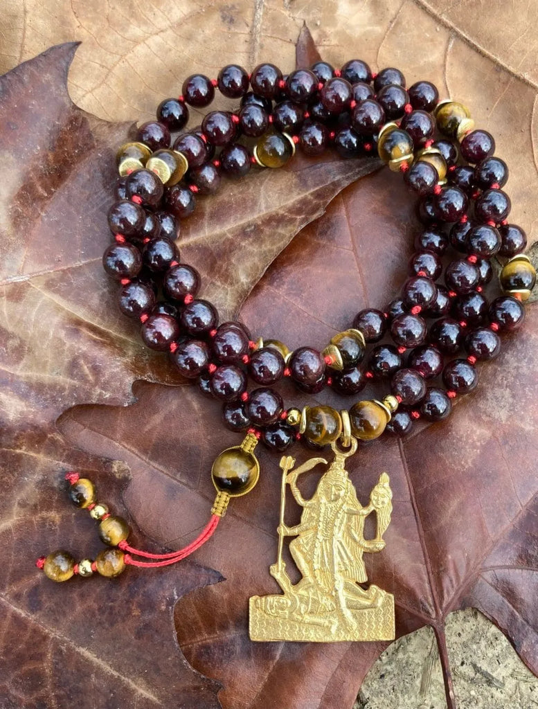 Japamālā Kalī in Granato, Ematite e Occhio di Tigre arrotolata su un tronco, simbolo di forza e radicamento.