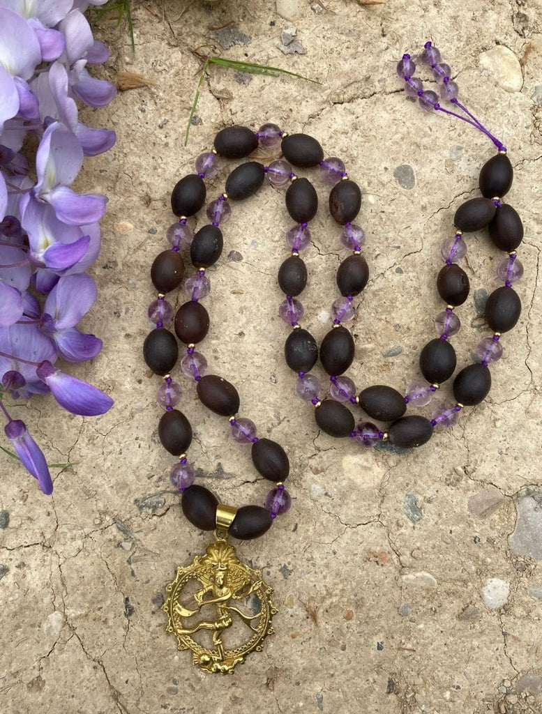 mala da 54 grani in semi di loto naturali ed ametista arricchita dal  pendente ottone raffigurante Shiva Nataraja. Disposta nella sua lunghezza per una visione d'insieme