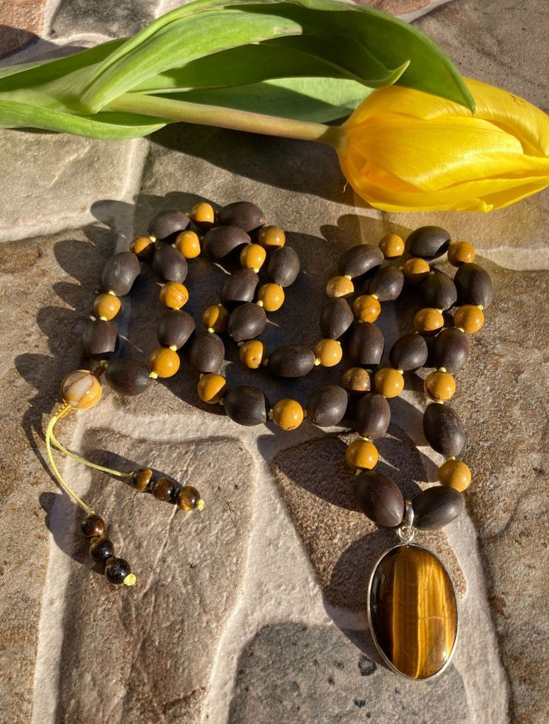 Mala con Semi di Loto, Mokaite e pendente Occhio di Tigre in argento. Dettaglio collana: focus sulle pietre e sul design. Dettaglio guru: grano centrale con ricamo macramé.
