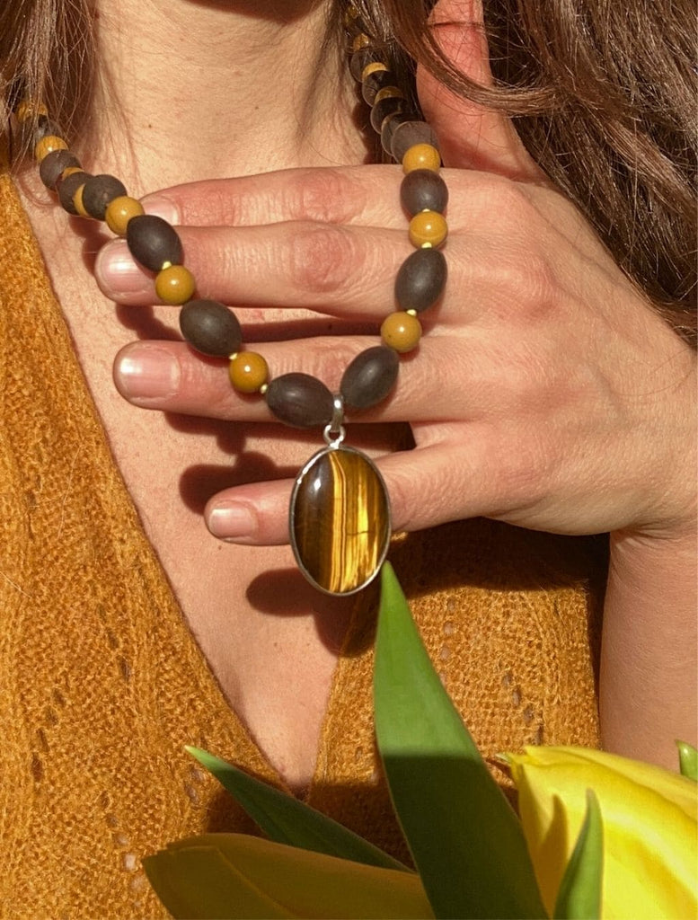 Mala con Semi di Loto, Mokaite e pendente Occhio di Tigre in argento. Indossata con la mano che la tiene in rilievo.
