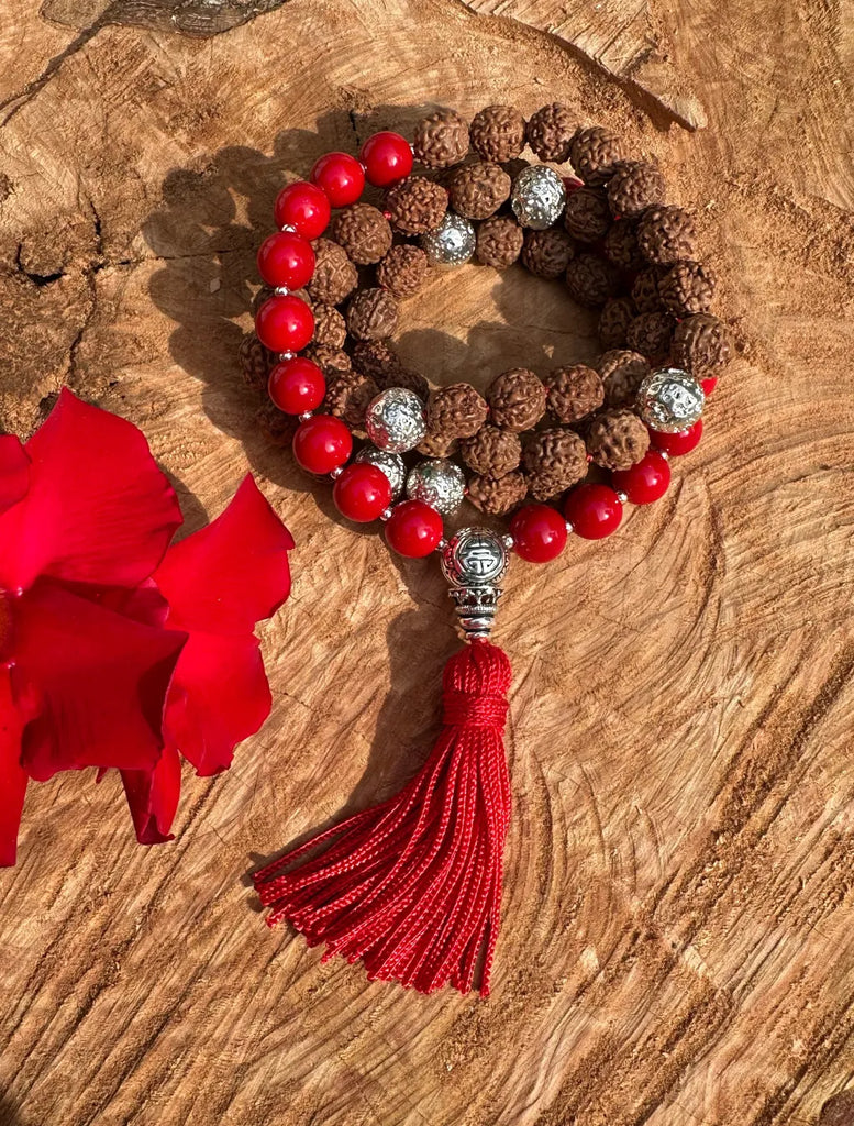 Japamala Umadevi fatta a mano con semi di Rudrākṣa, appoggiata su un tronco naturale, simbolo di forza e radicamento.